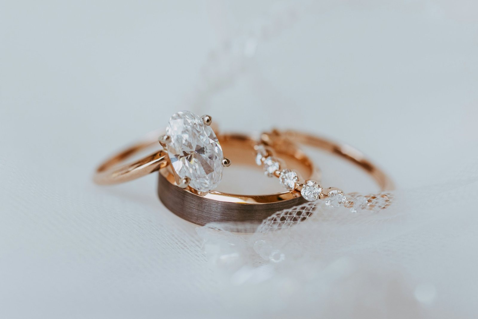 A diamond engagement ring and two wedding bands on ivory tulle